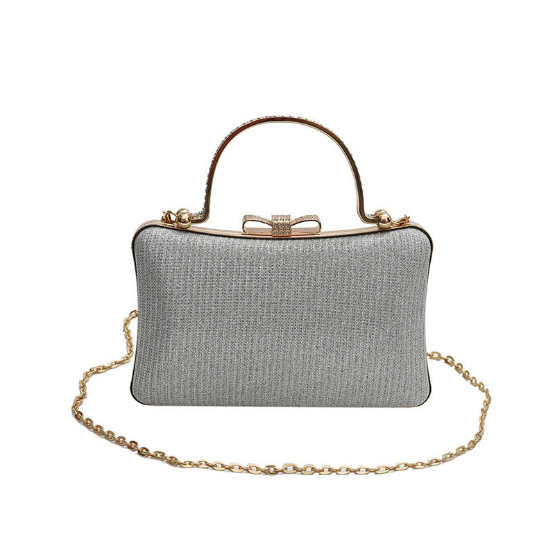 Silver clutch bag with gold chain and handle on a white background