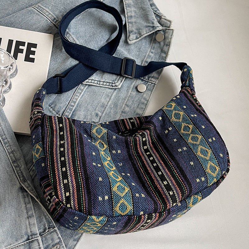 Blue patterned bag with a denim jacket and magazine on a light gray background