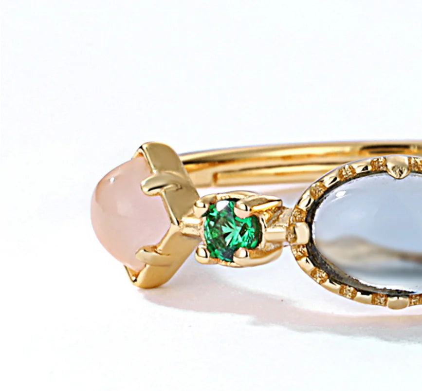 Close-up of three gold rings with different gemstones on a white background