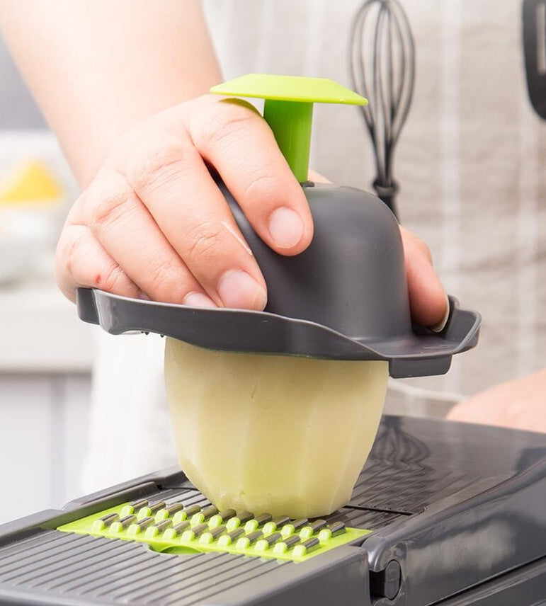 Person using a green and gray kitchen tool on a cutting board with a blurred background
