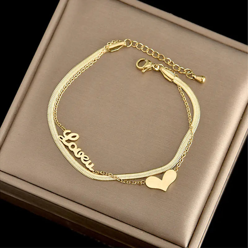 Gold bracelet with 'Love' and heart charm on a brown box