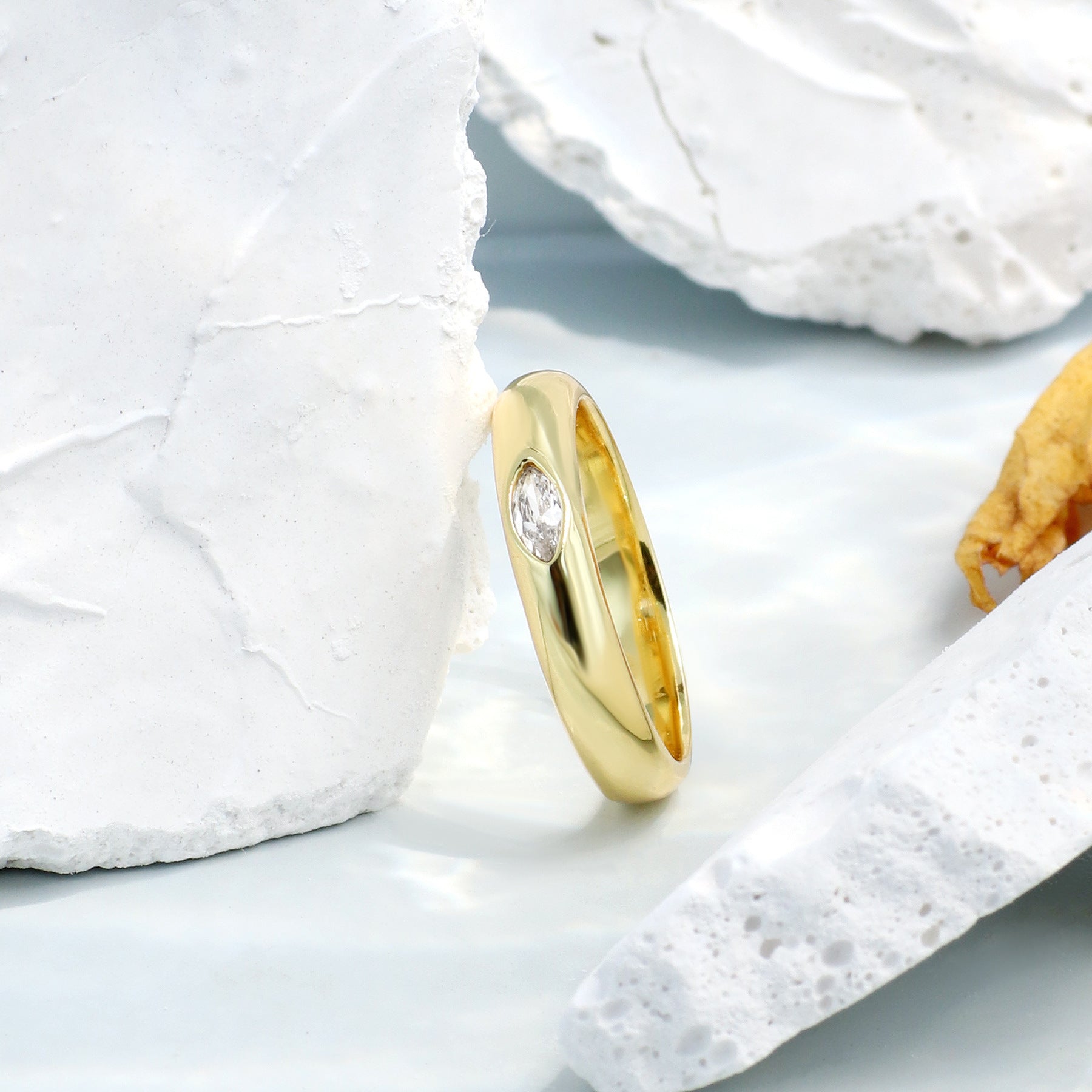 Gold ring with a diamond on a light blue surface with white stones