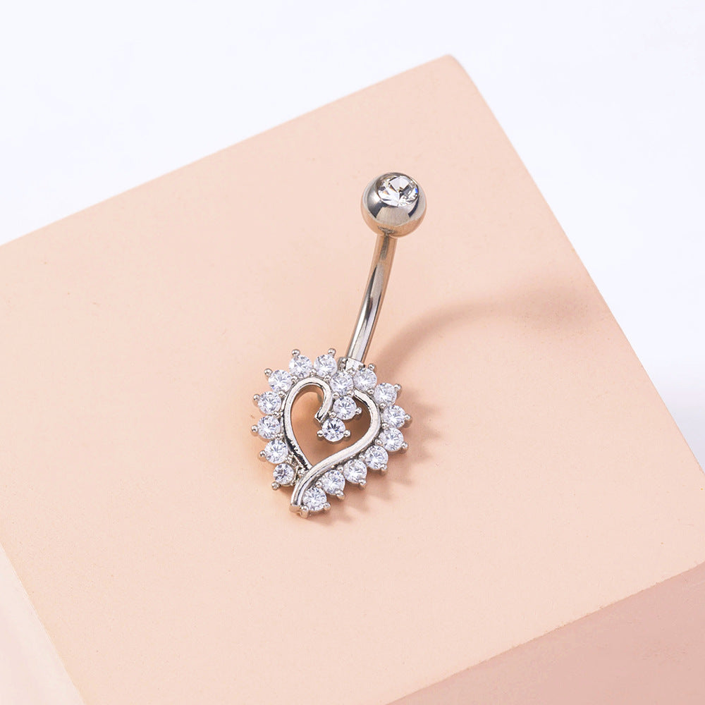 Silver belly button ring with heart design on a beige background