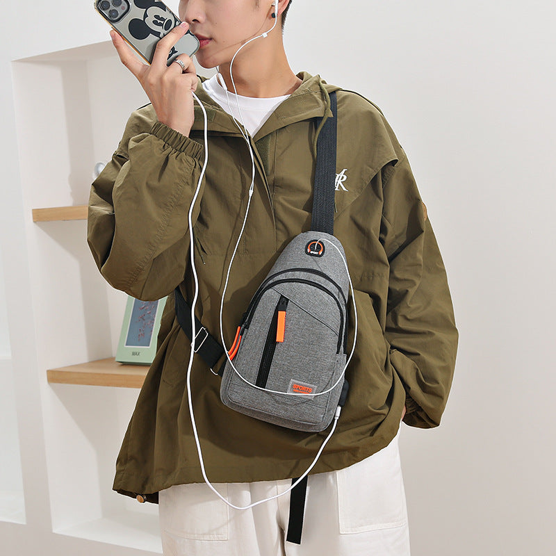 Person wearing a green jacket with a gray backpack, holding a phone and earphones.
