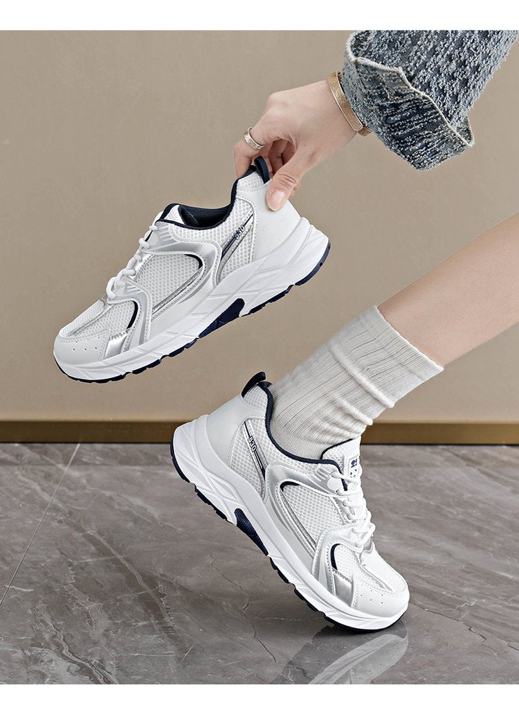 Person wearing white sneakers with black soles on a neutral background