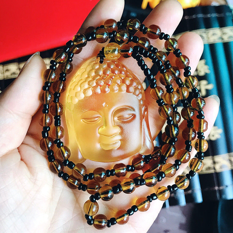 Beaded necklace with Buddha pendant held in a hand against a blurred background