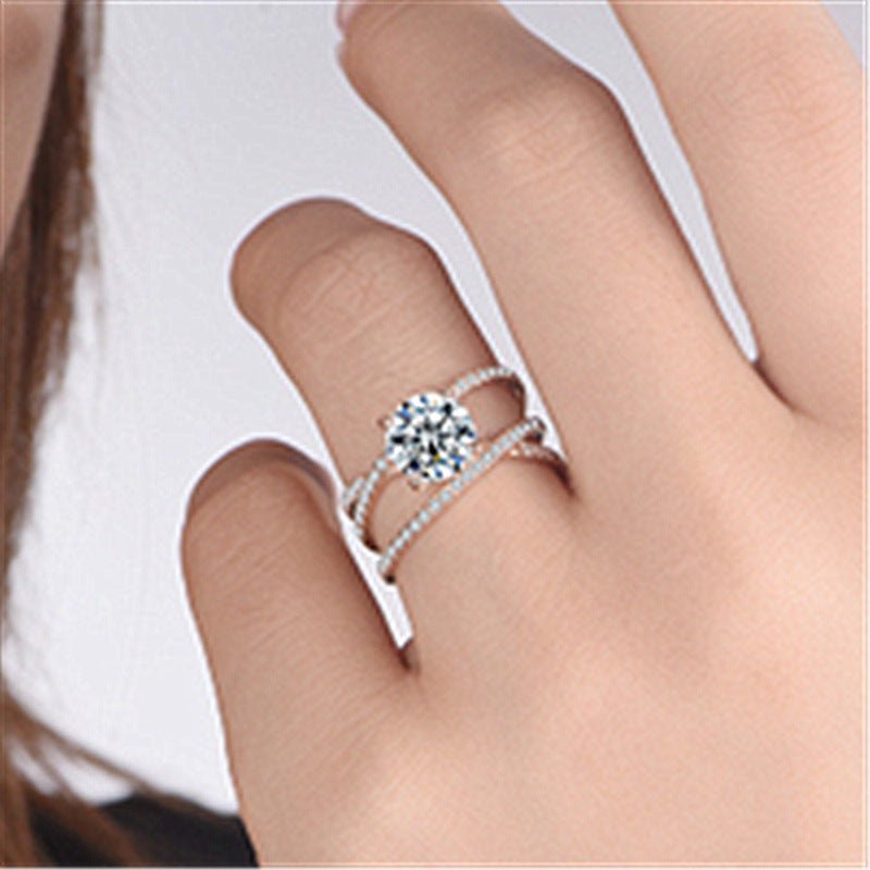 Close-up of a hand wearing two silver rings with clear gemstones on a light background