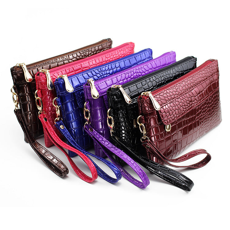Set of colorful crocodile-textured handbags with wristlets on a white background