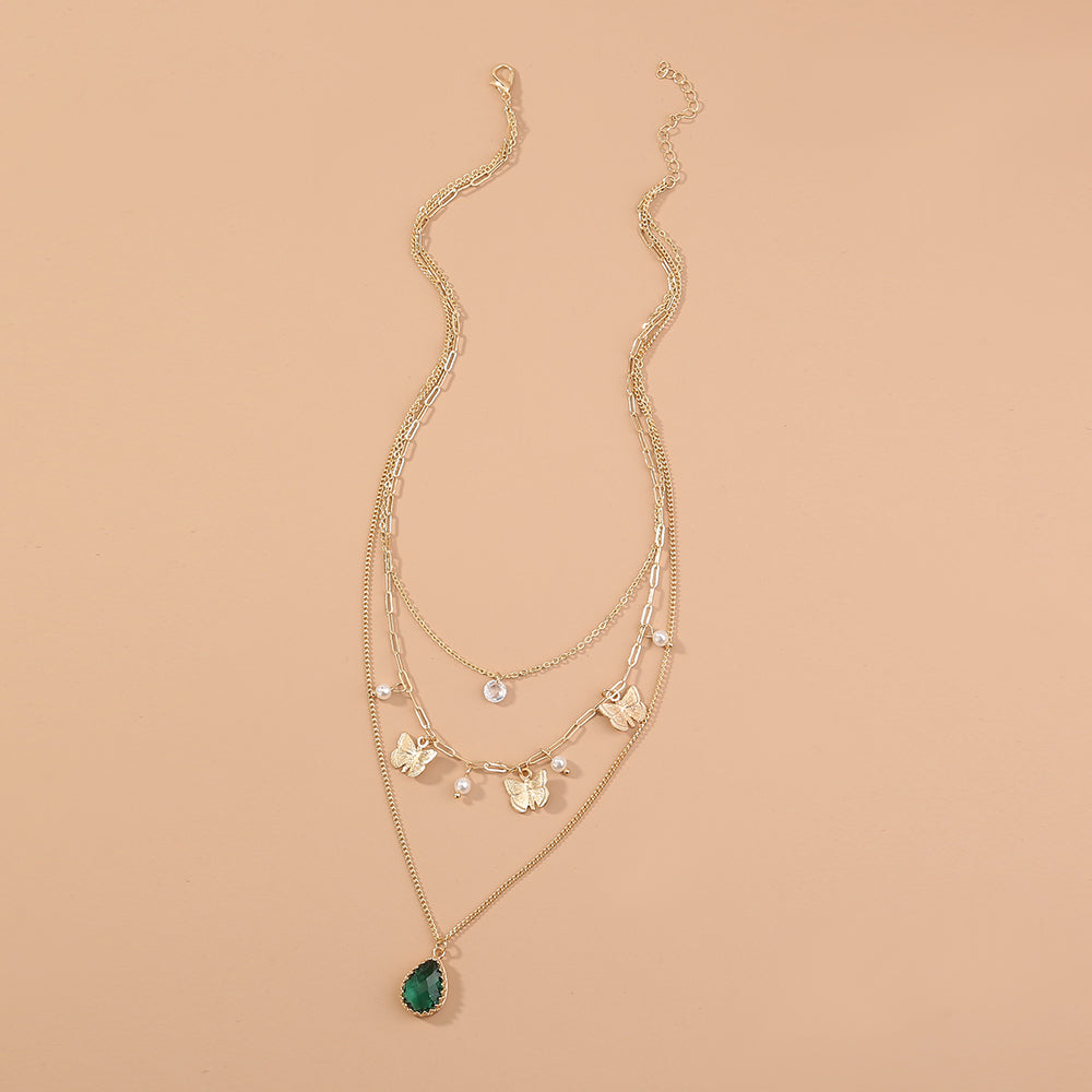 Gold necklace with green pendant on a beige background
