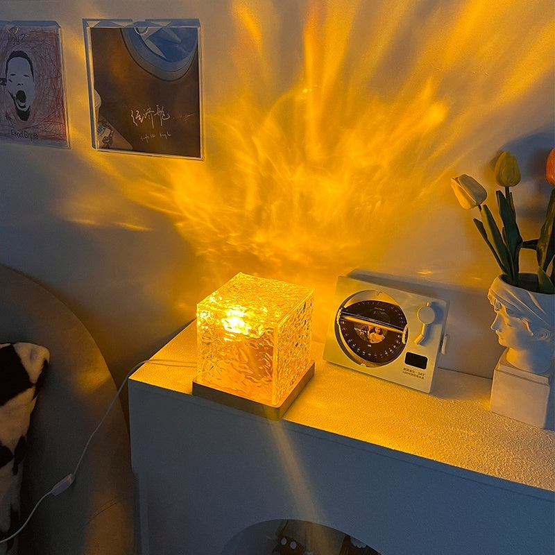 Crystal cube light emitting a warm glow on a shelf with decorative items.