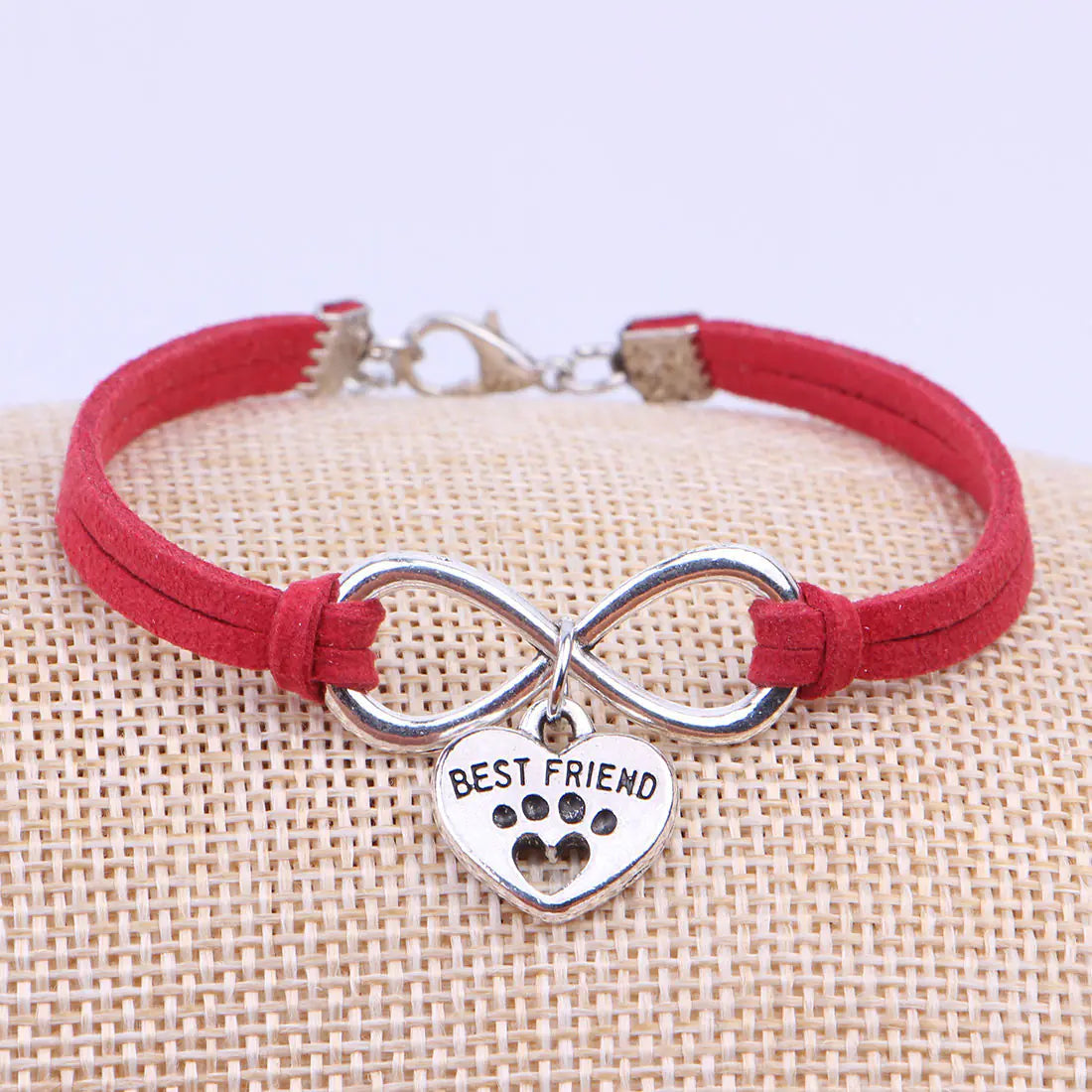 Red bracelet with silver infinity symbol and 'Best Friend' charm on a beige surface