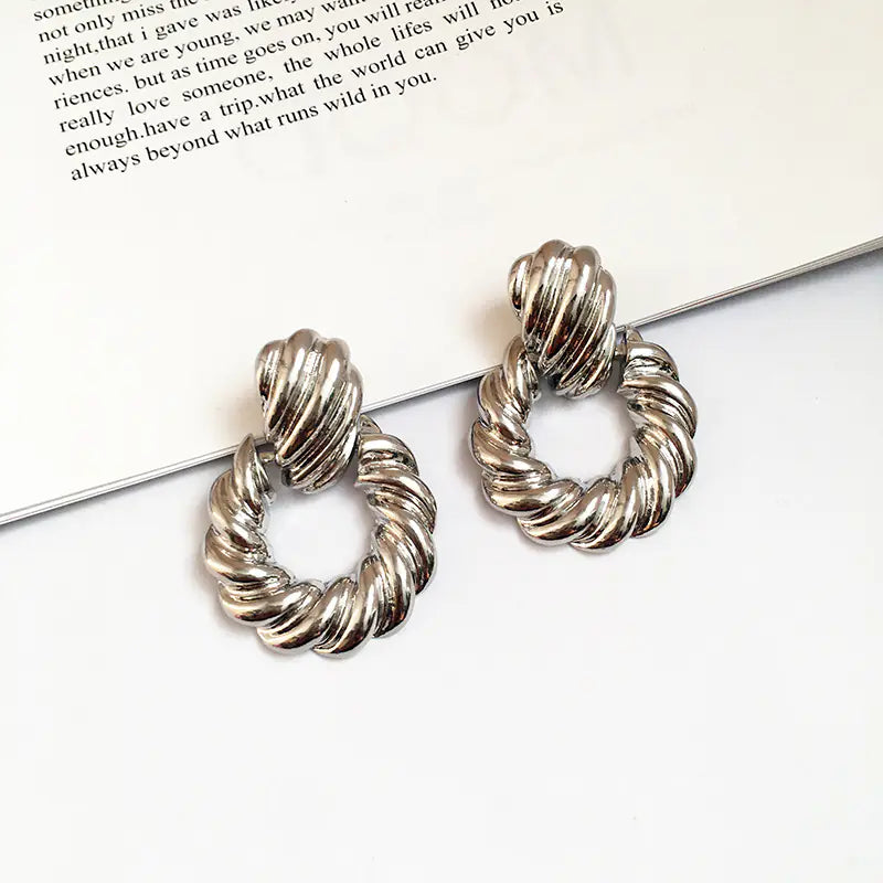 Silver hoop earrings on a white surface with text in the background