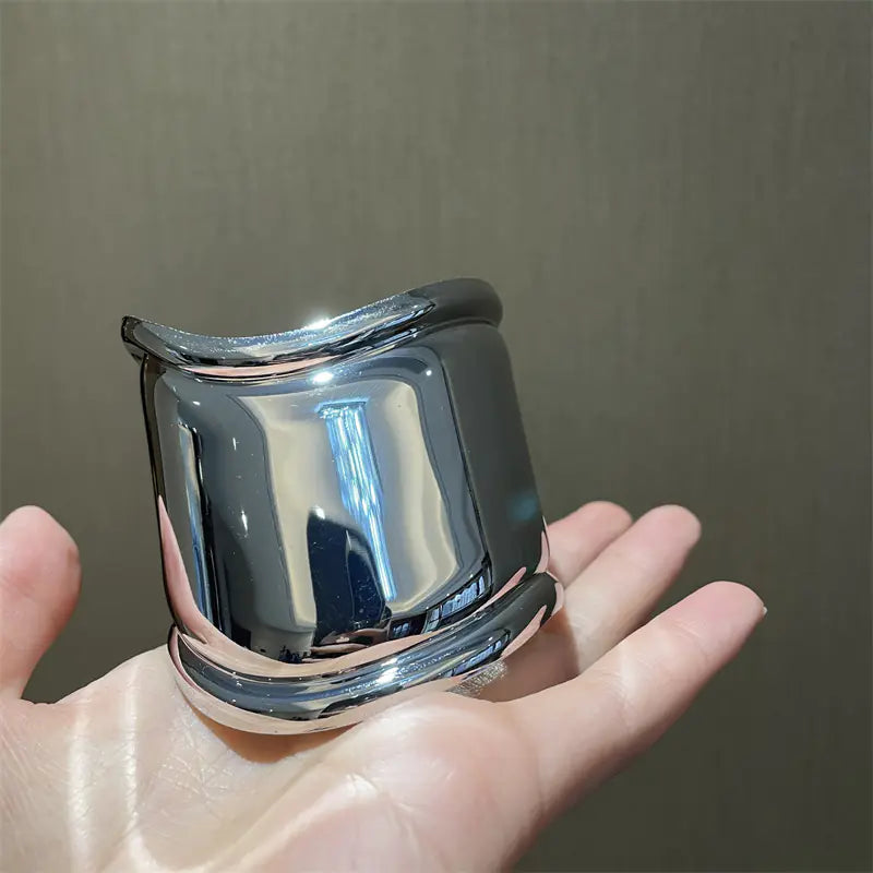 Chrome ring held in a hand against a neutral background
