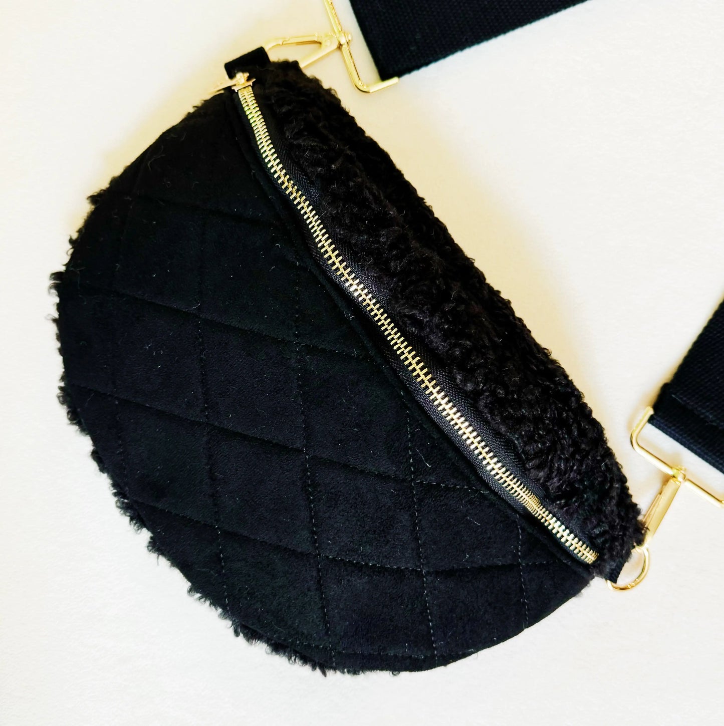 Black quilted bag with gold zipper on a light background
