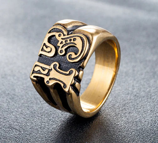 Gold ring with intricate design on a gray background