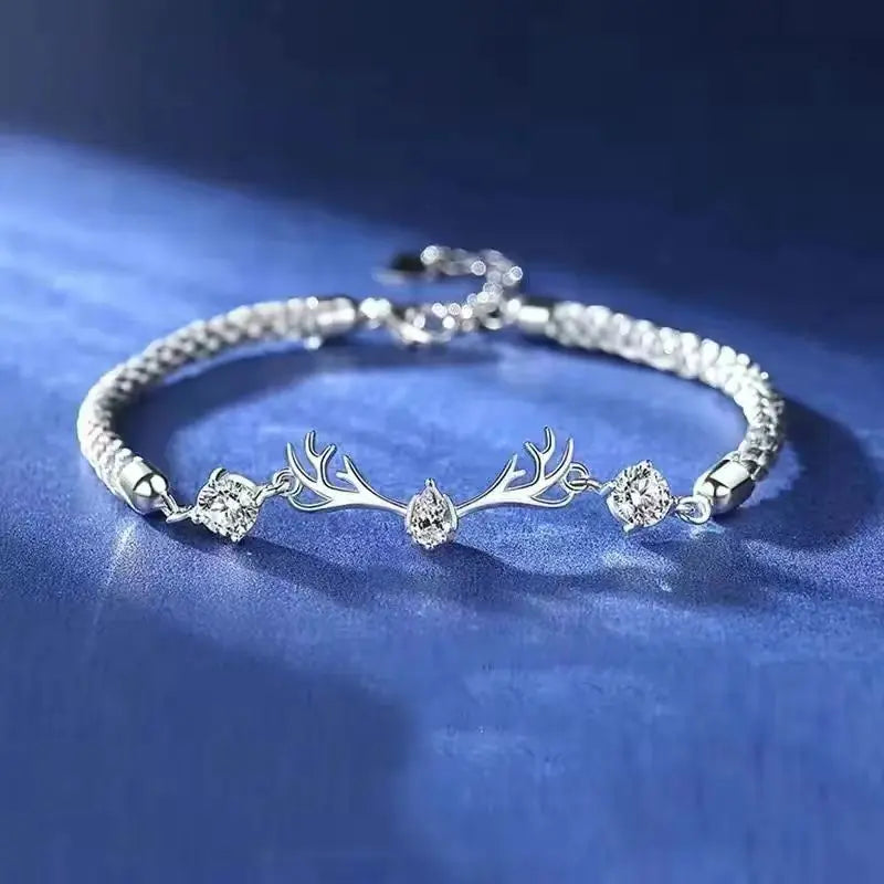 Silver bracelet with deer antler design on a blue fabric background
