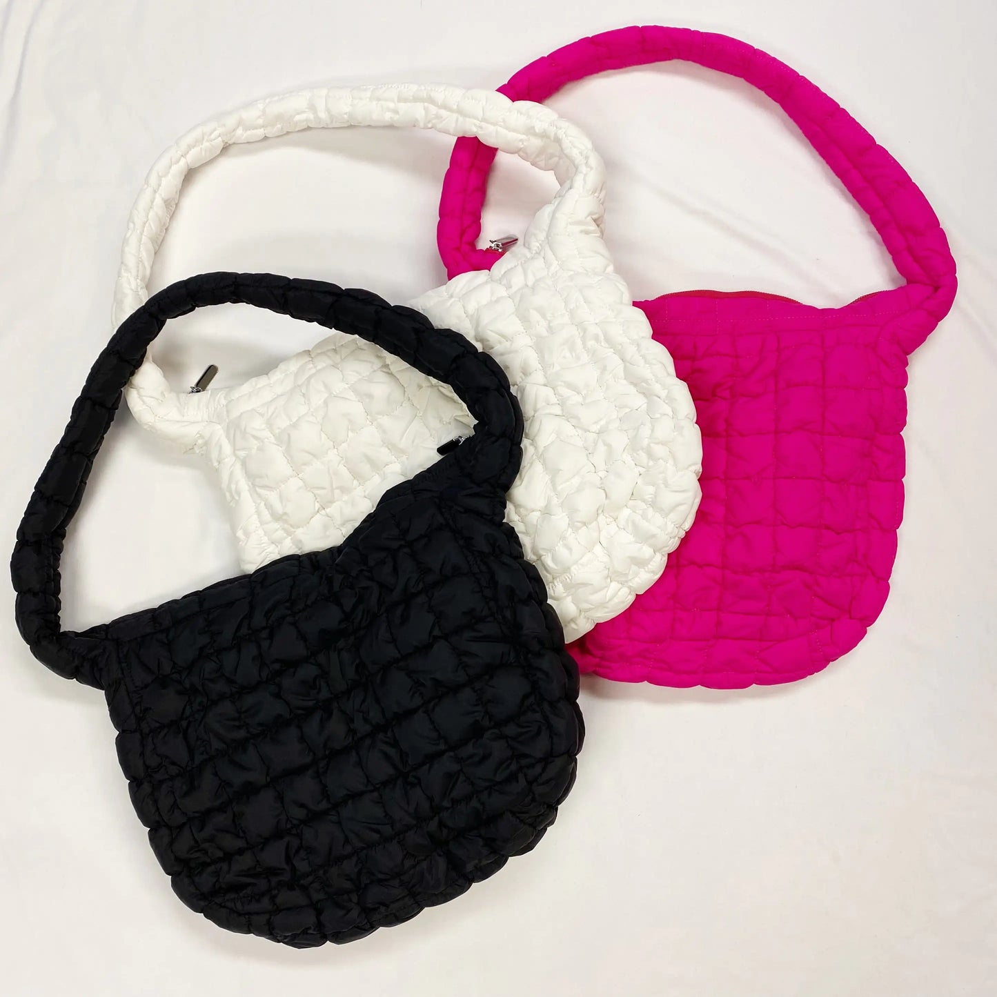 Three textured bags in black, white, and pink on a white background