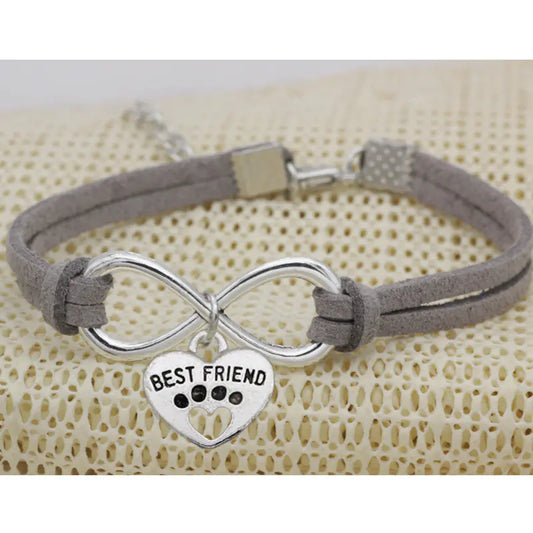 Bracelet with infinity symbol and 'Best Friend' heart charm on a textured beige background
