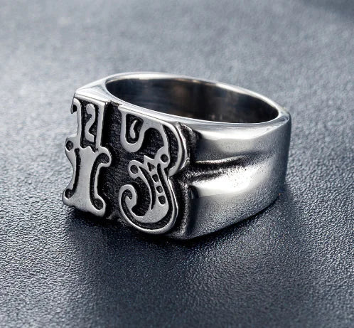 Silver ring with intricate design on a dark surface