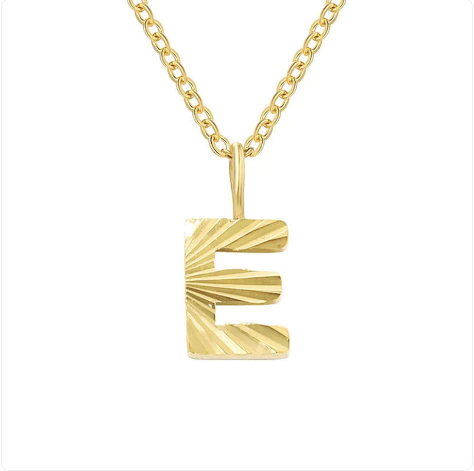 Gold necklace with a textured 'E' pendant on a white background