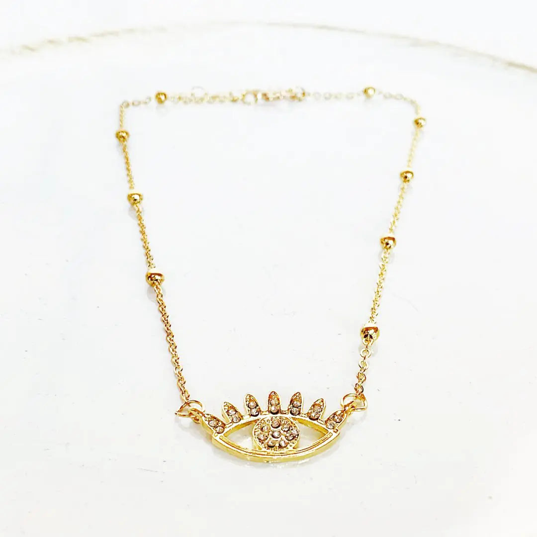 Gold necklace with an eye-shaped pendant on a white background