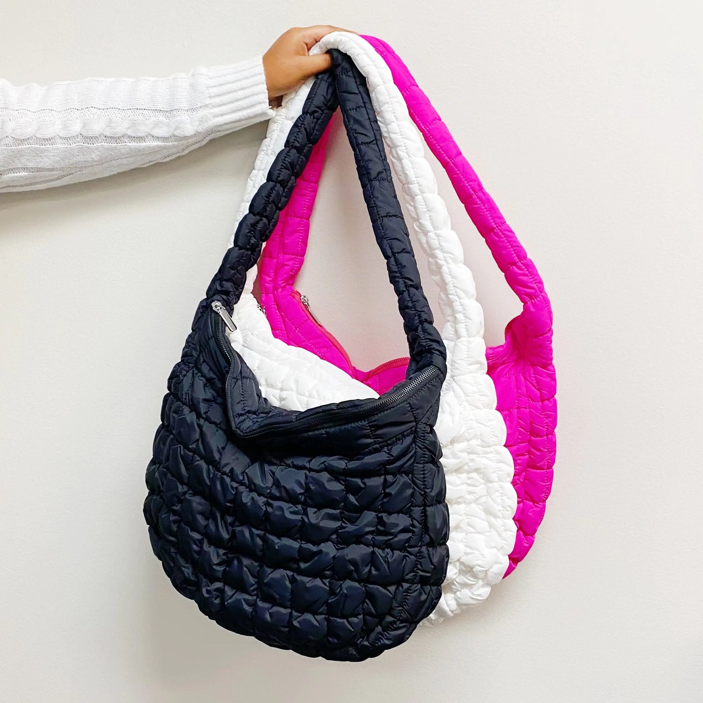Multicolored quilted handbag held by a person on a light background