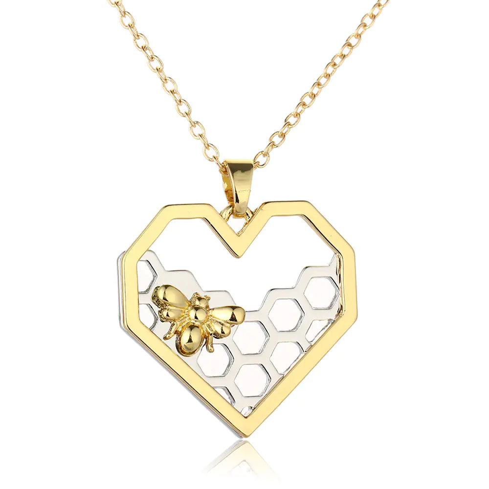 Gold necklace with a heart-shaped pendant featuring a honeycomb design and a bee on a white background.