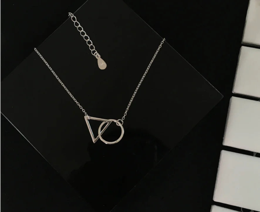 Silver necklace with geometric pendant on a black surface