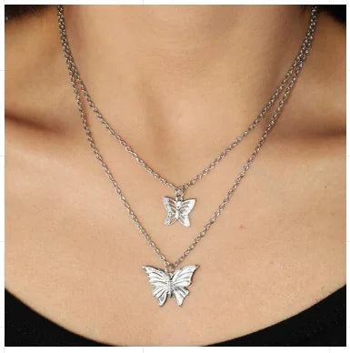 Two silver butterfly necklaces on a person's neck
