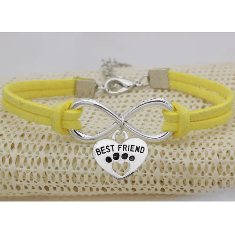 Yellow bracelet with silver infinity charm and 'Best Friend' heart charm on a textured surface