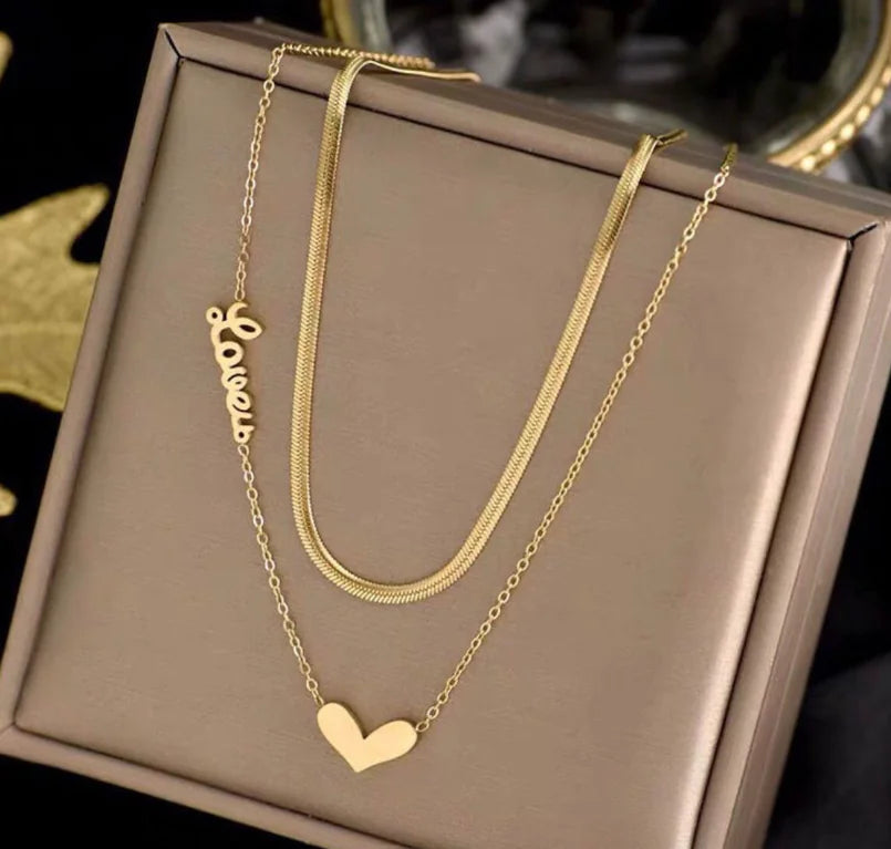 Gold necklace with 'Love' pendant on a brown jewelry box