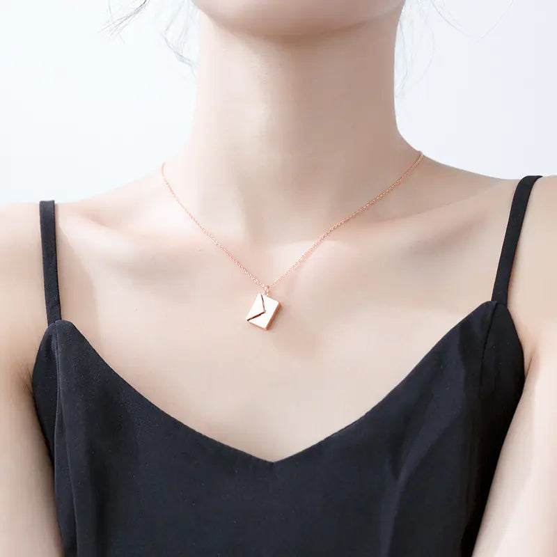 Necklace with a heart-shaped pendant worn by a person in a black top on a white background