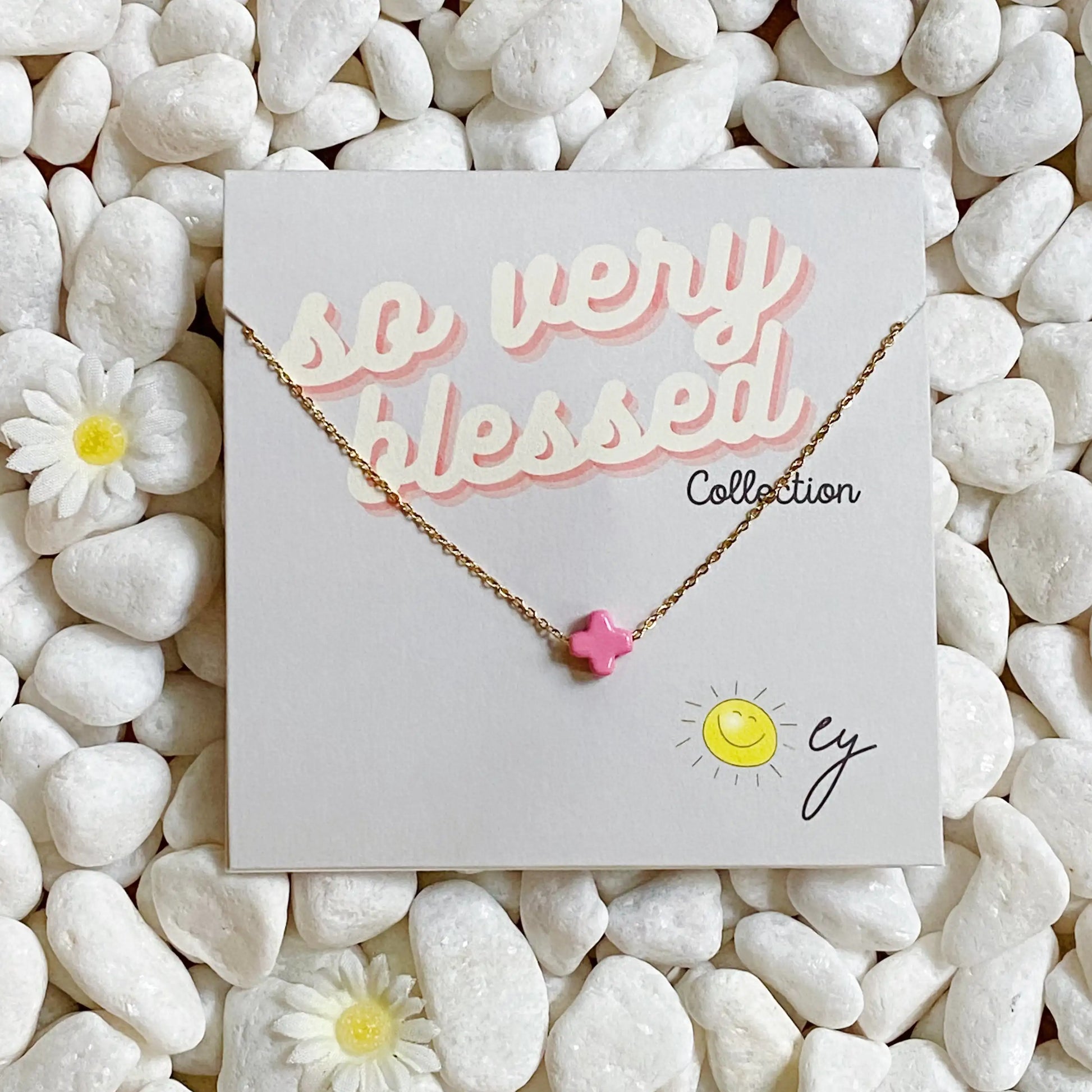 Necklace with a pink star charm on a 'so very blessed' card with pebbles and flowers in the background
