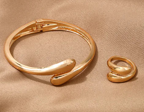 Gold bracelet and ring set on a beige fabric background
