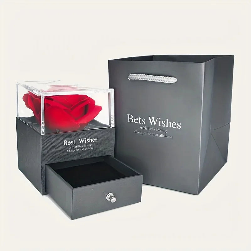 Black gift box with a red rose inside and a matching black gift bag on a white background.