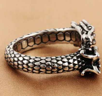 Silver ring with snake design on a beige background