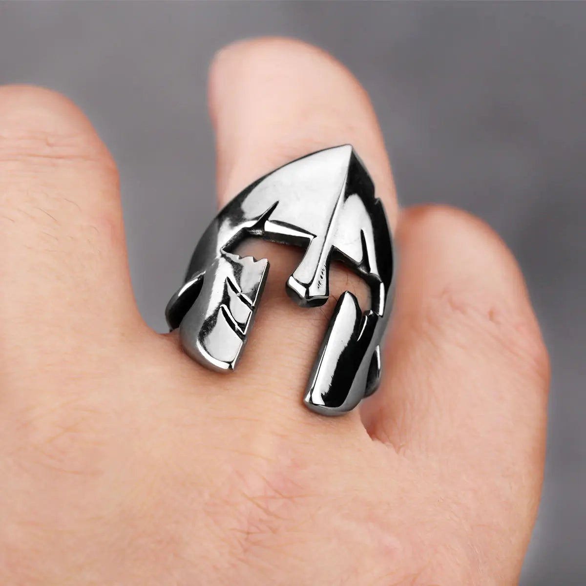 Silver ring with a unique design on a finger against a neutral background