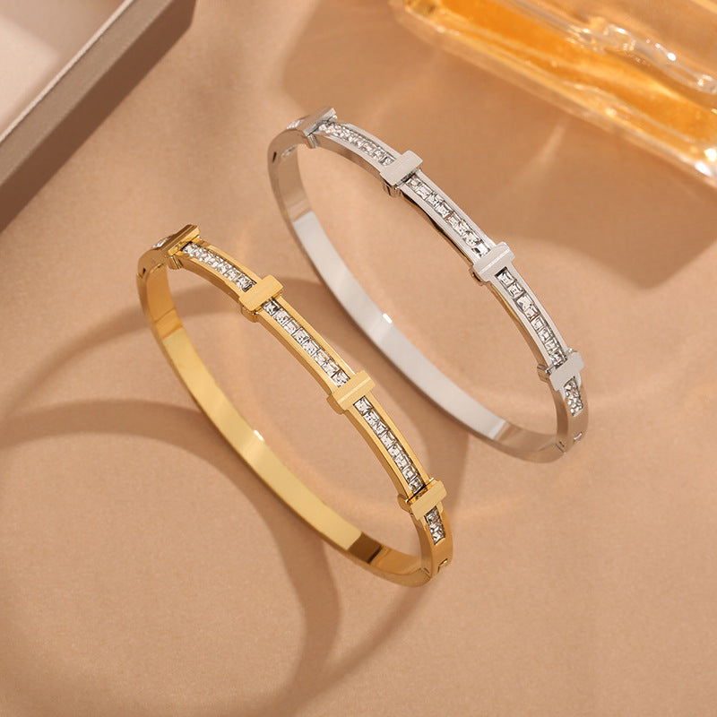 Gold and silver bracelets with diamond accents on a beige surface