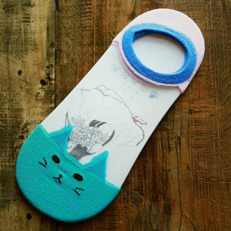 Cat-themed sock with blue and green accents on a wooden surface