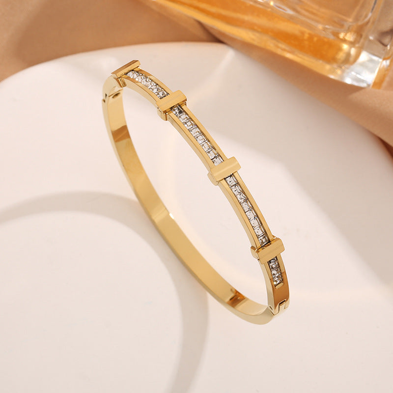 Gold bracelet with embedded diamonds on a light background