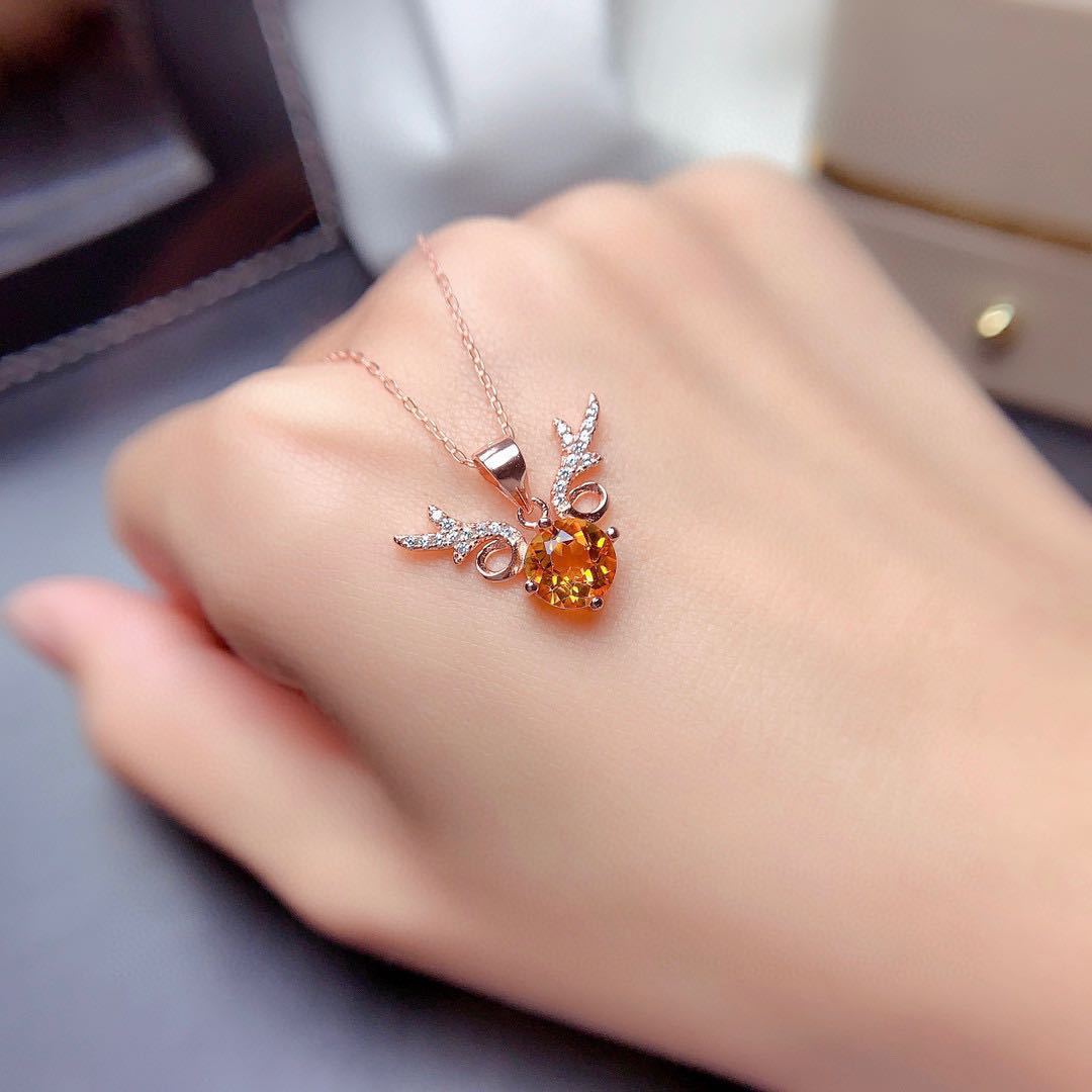 Jewelry with an orange gemstone on a hand against a neutral background