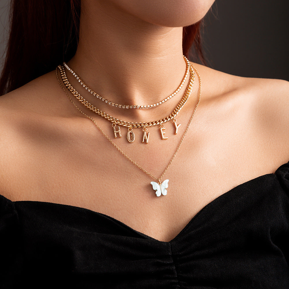 Necklace with 'HONEY' pendant on a person wearing a black top against a dark background