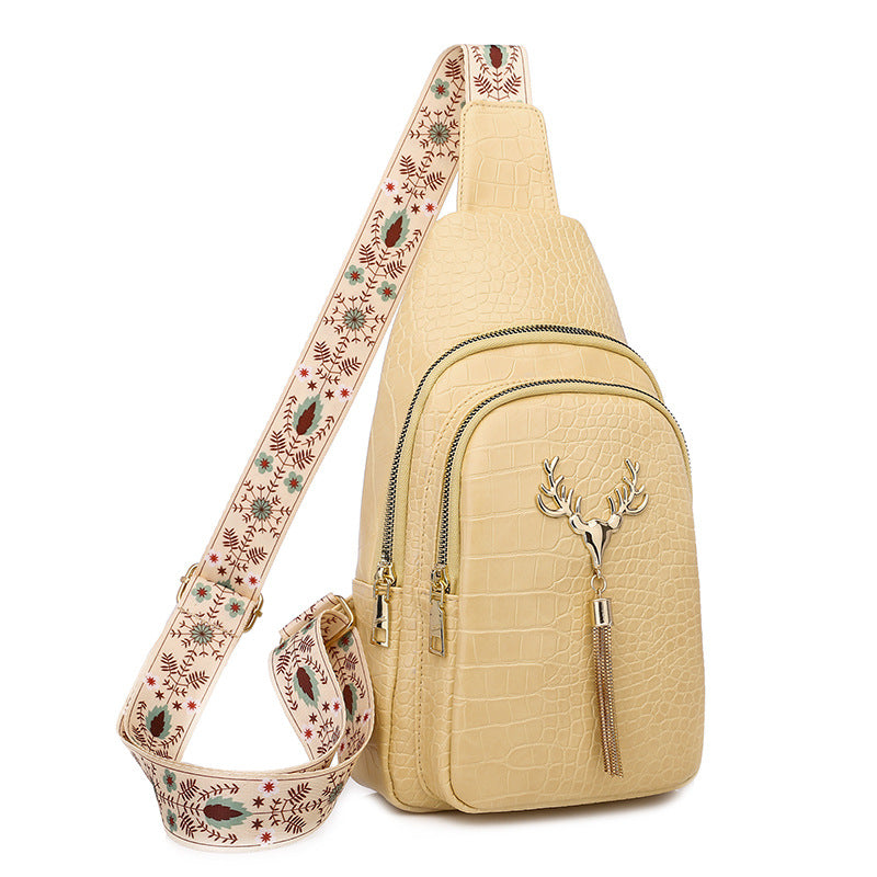 Beige crossbody bag with floral strap on a white background