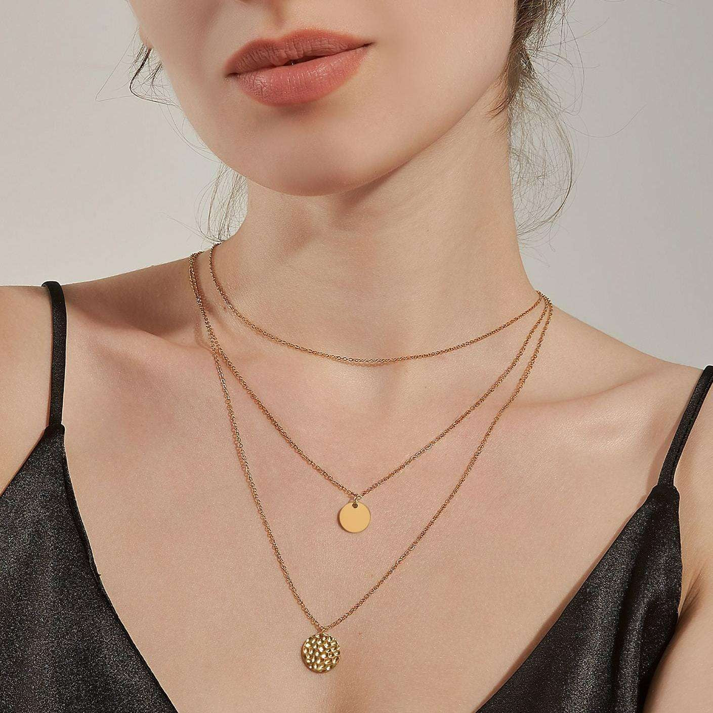 Close-up of a woman wearing gold necklaces with a plain background