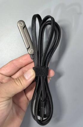 Black lanyard with metal clip held by a hand on a light gray background