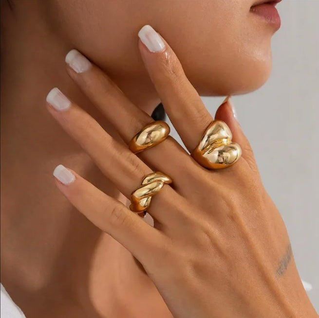 Close-up of a hand wearing gold rings with a neutral background