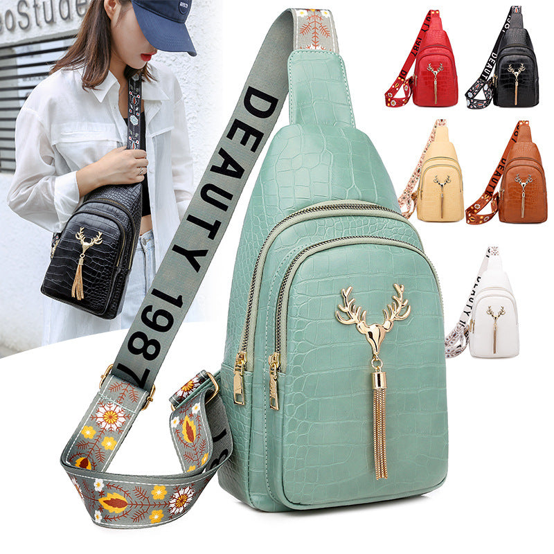 Mint green crossbody bag with deer charm and floral strap, surrounded by other bags.
