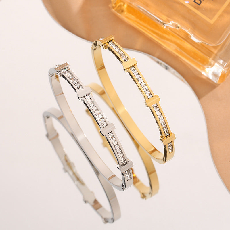 Two gold and silver bracelets with clear stones on a light background