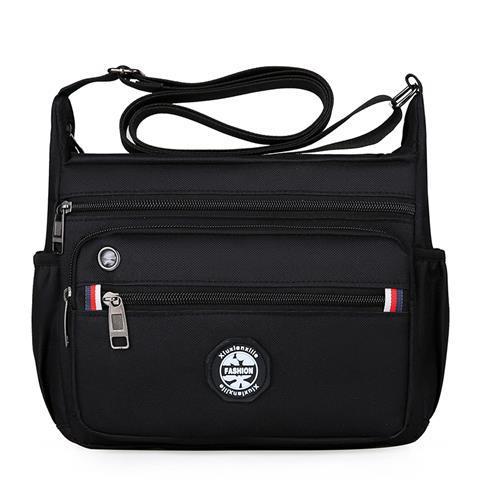 Black crossbody bag with multiple zippers on a white background