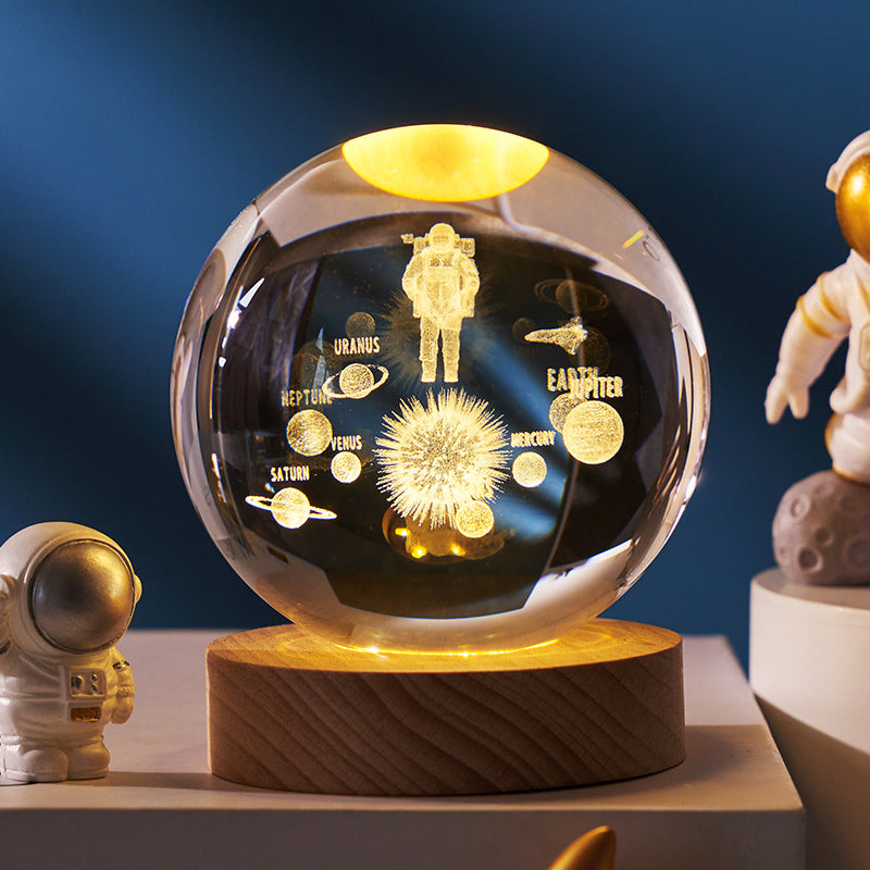 Decorative sphere with astronaut and solar system design on a wooden base against a dark blue background.